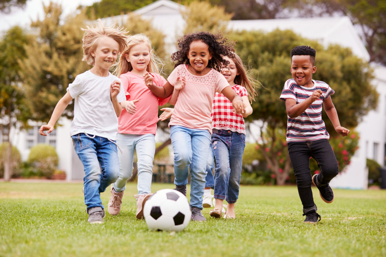 A group of children playing soccer in the grass.