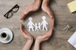 A paper cut out of a family with hands around it.