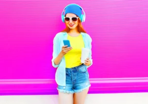 A woman wearing headphones and holding a cell phone.
