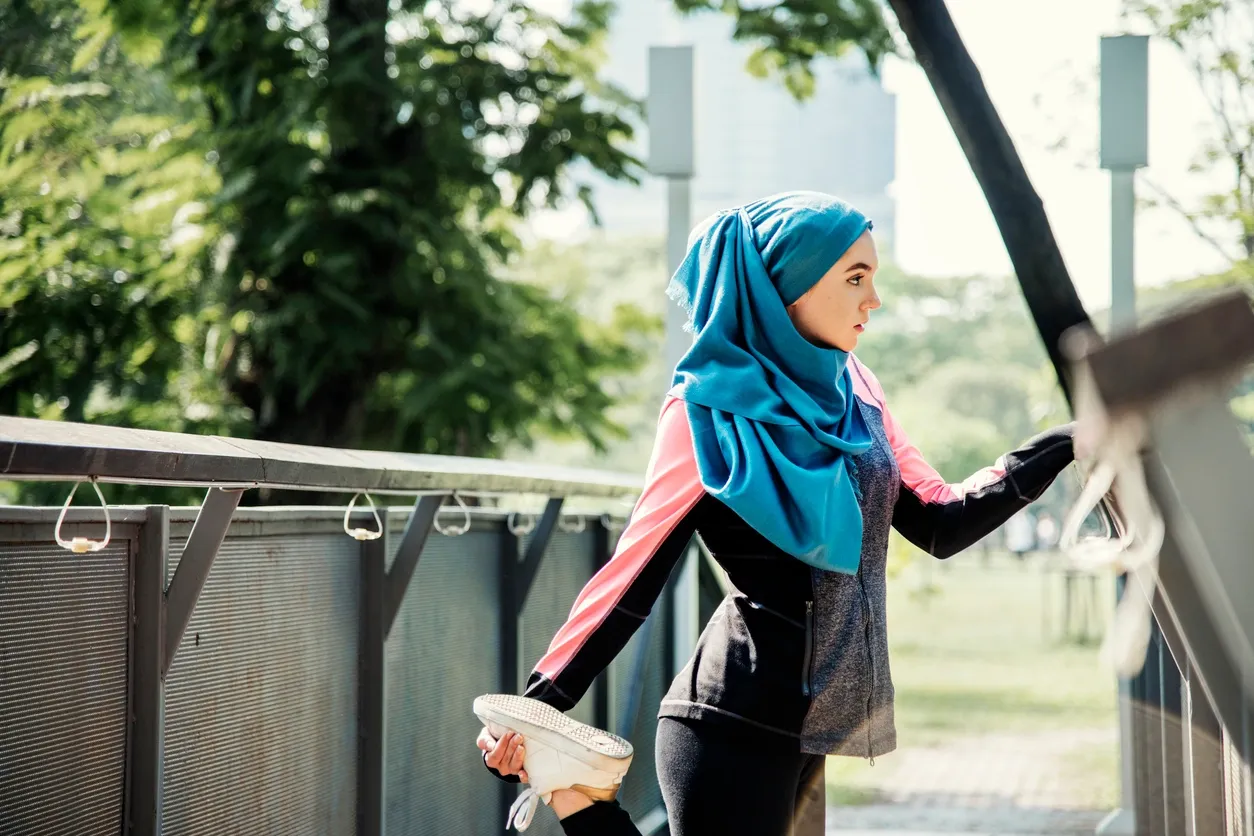 A woman in a hijab walking on the sidewalk.