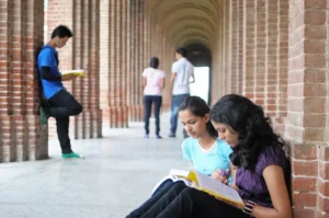 Two students are sitting on the ground reading.