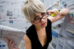 A woman with glasses is holding a phone