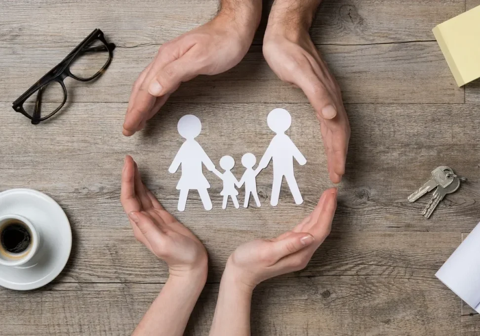 A paper cut out of a family with hands around it.