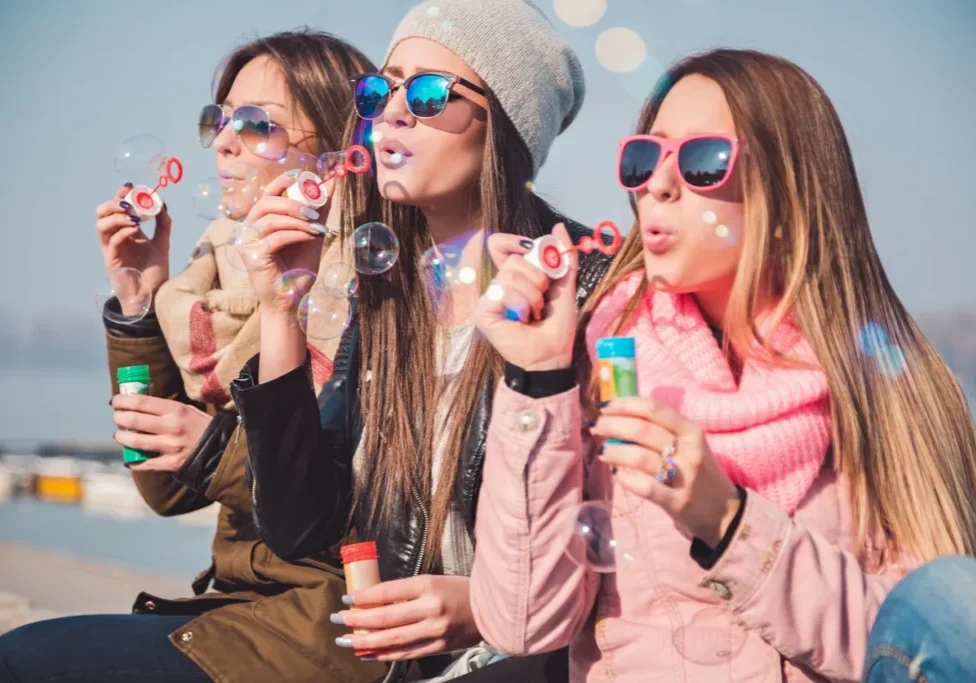 Three women blowing bubbles with soap bubbles.